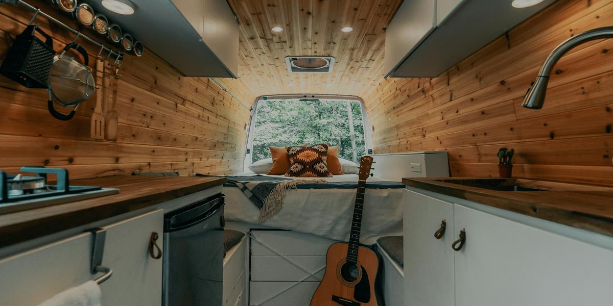 Cozy wood-paneled camper van interior with a compact kitchen